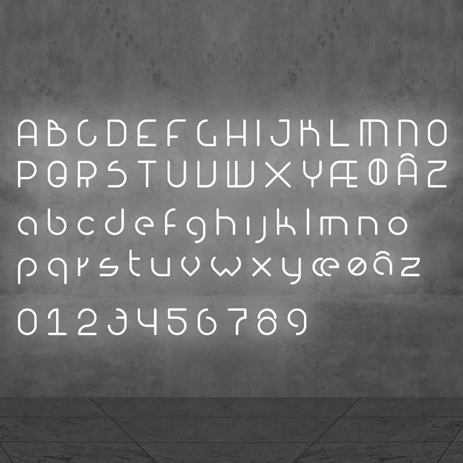 Alphabet complet, majuscules, minuscules et chiffres, affiché en lettres LED blanches sur un mur.