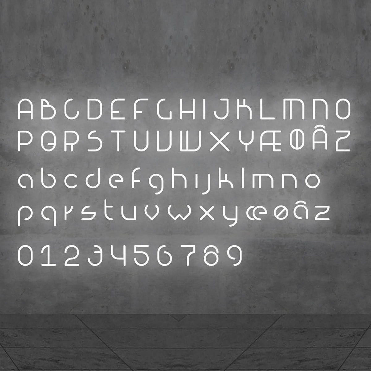Alphabet complet en lettres lumineuses blanches, chiffres inclus, sur mur gris