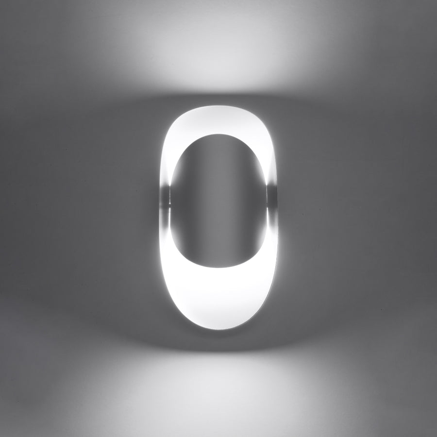 Luminaire allumé dans la pénombre, halo lumineux diffus autour du boîtier ovale