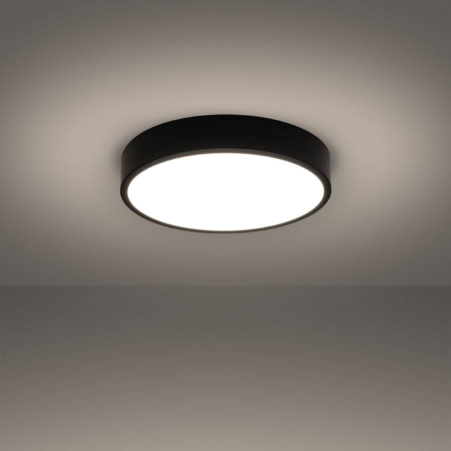 Plafonnier allumé dans une pièce sombre, halo lumineux diffusé sur le plafond