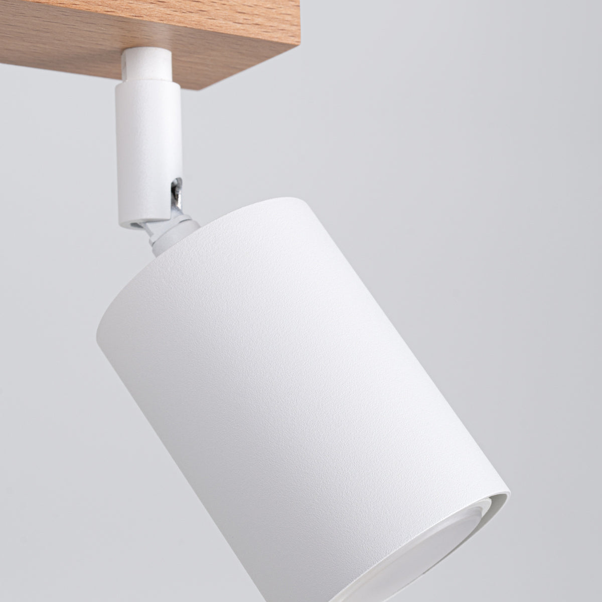 Détail en gros plan d'un spot blanc orientable, articulation et finition mate texturée.
