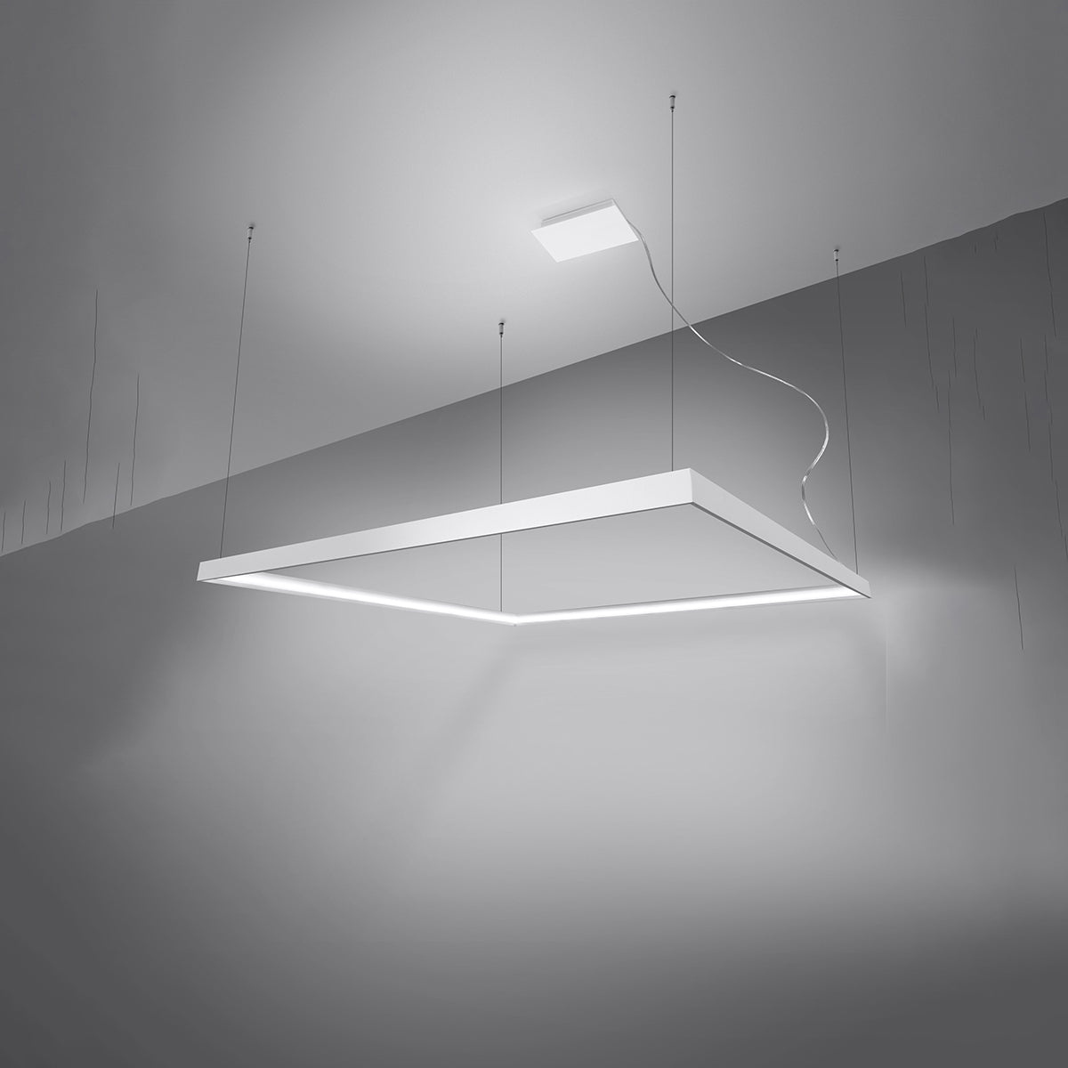 Vue en perspective du luminaire allumé, suspendu au plafond dans une pièce sombre.