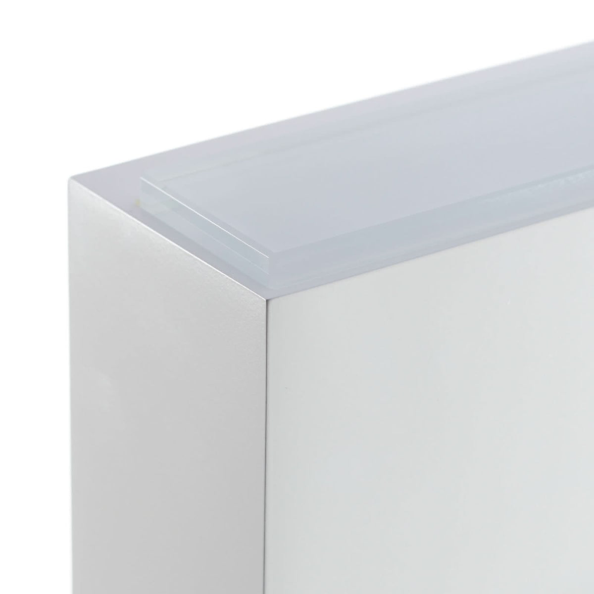 Détail d’angle montrant l’épaisseur du verre et la finition mate blanche.