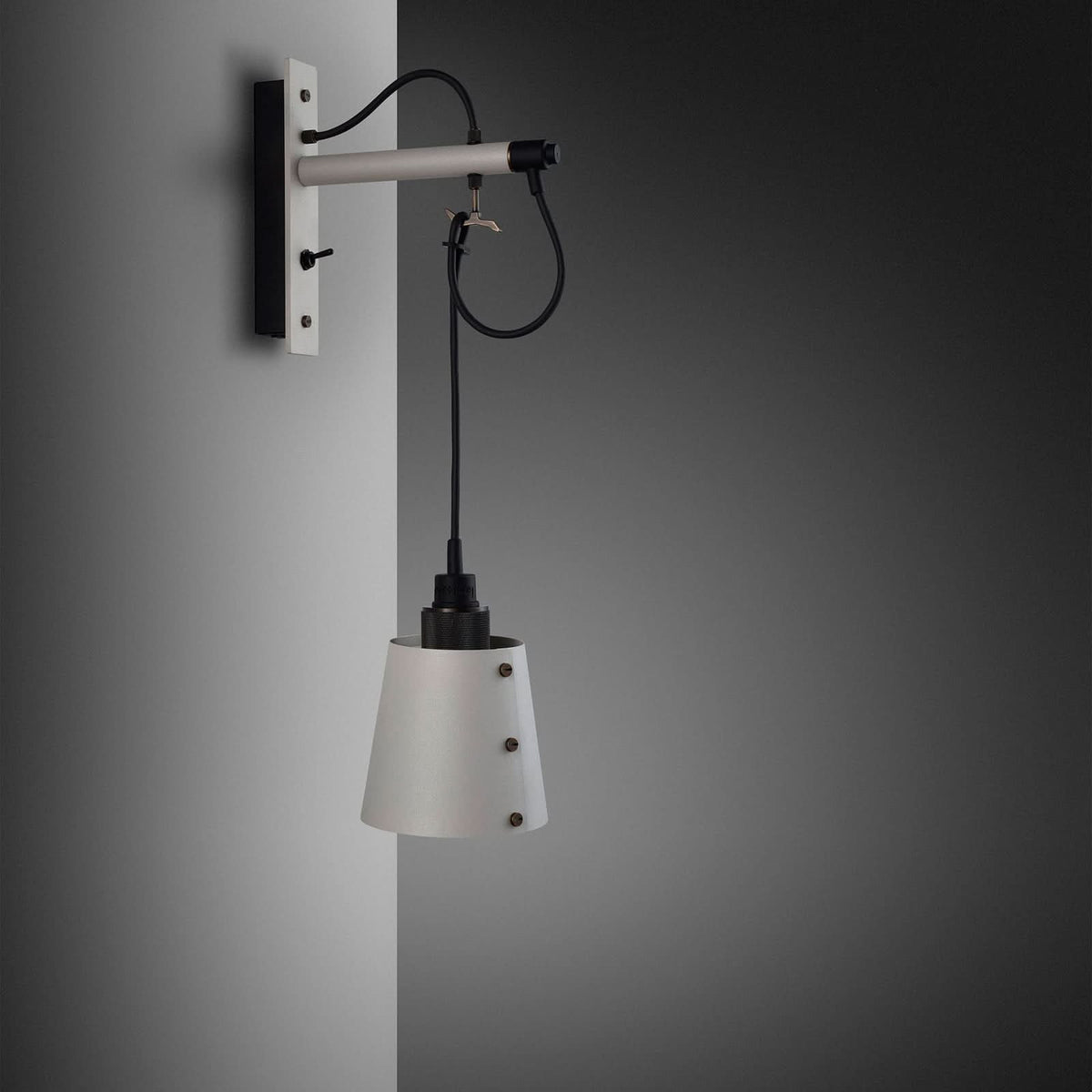 Vue de trois quarts sur mur gris, montrant la platine, le bras et le câble bouclé.