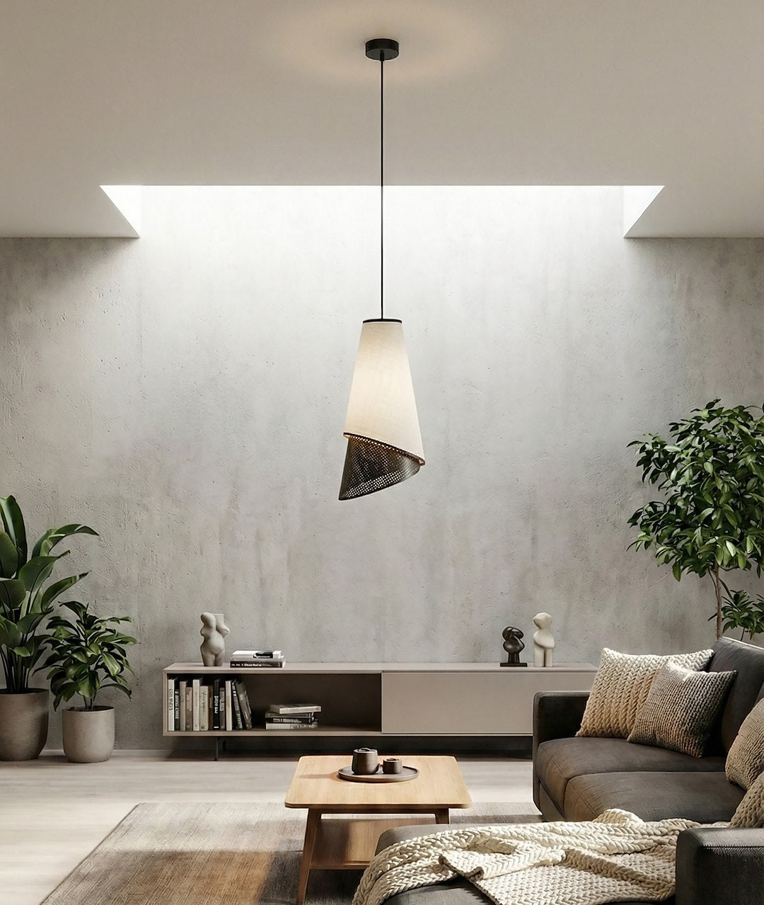 Pièce à vivre béton, suspension au-dessus table basse, canapé et plantes vertes.
