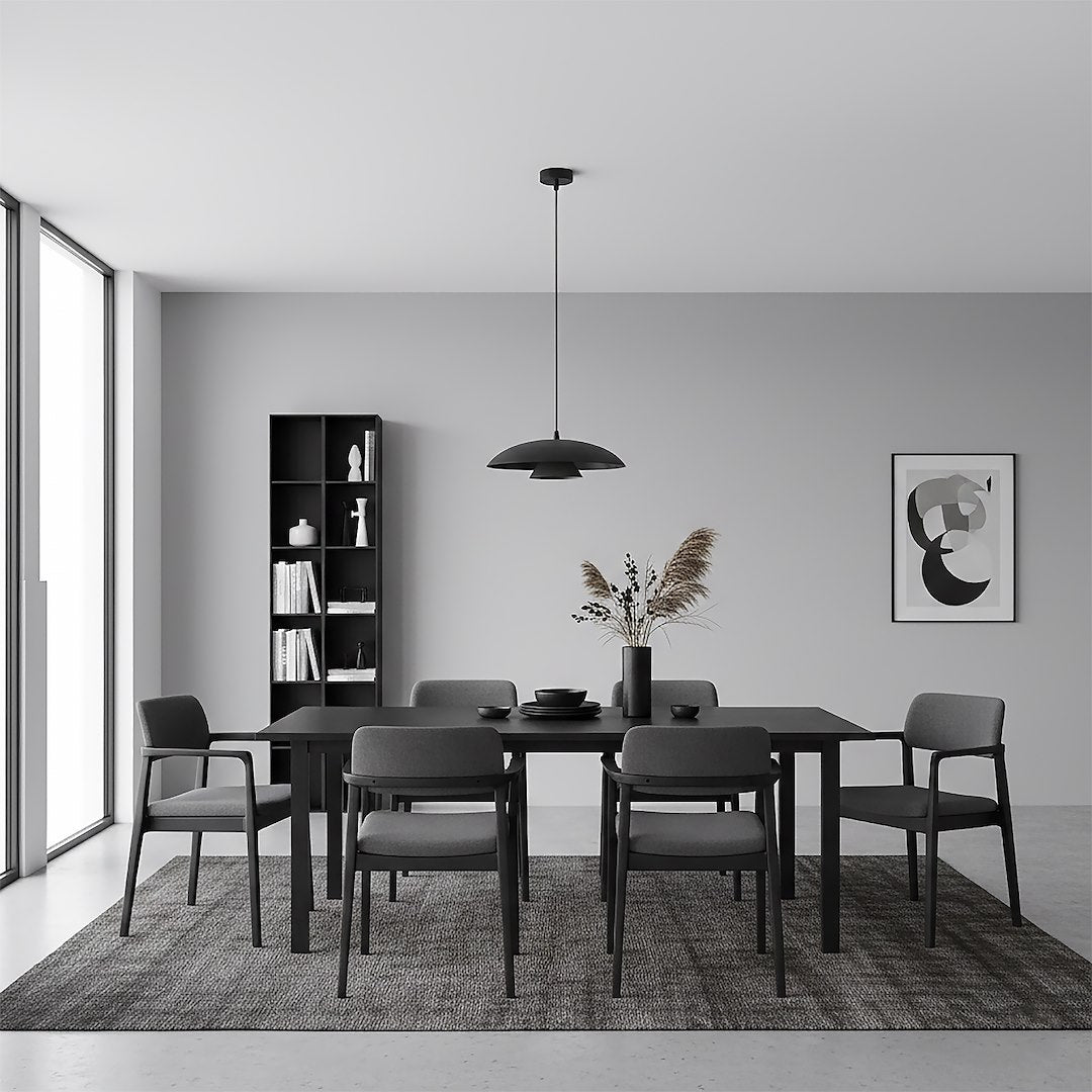 Suspension noire éclairant une salle à manger grise avec table et chaises