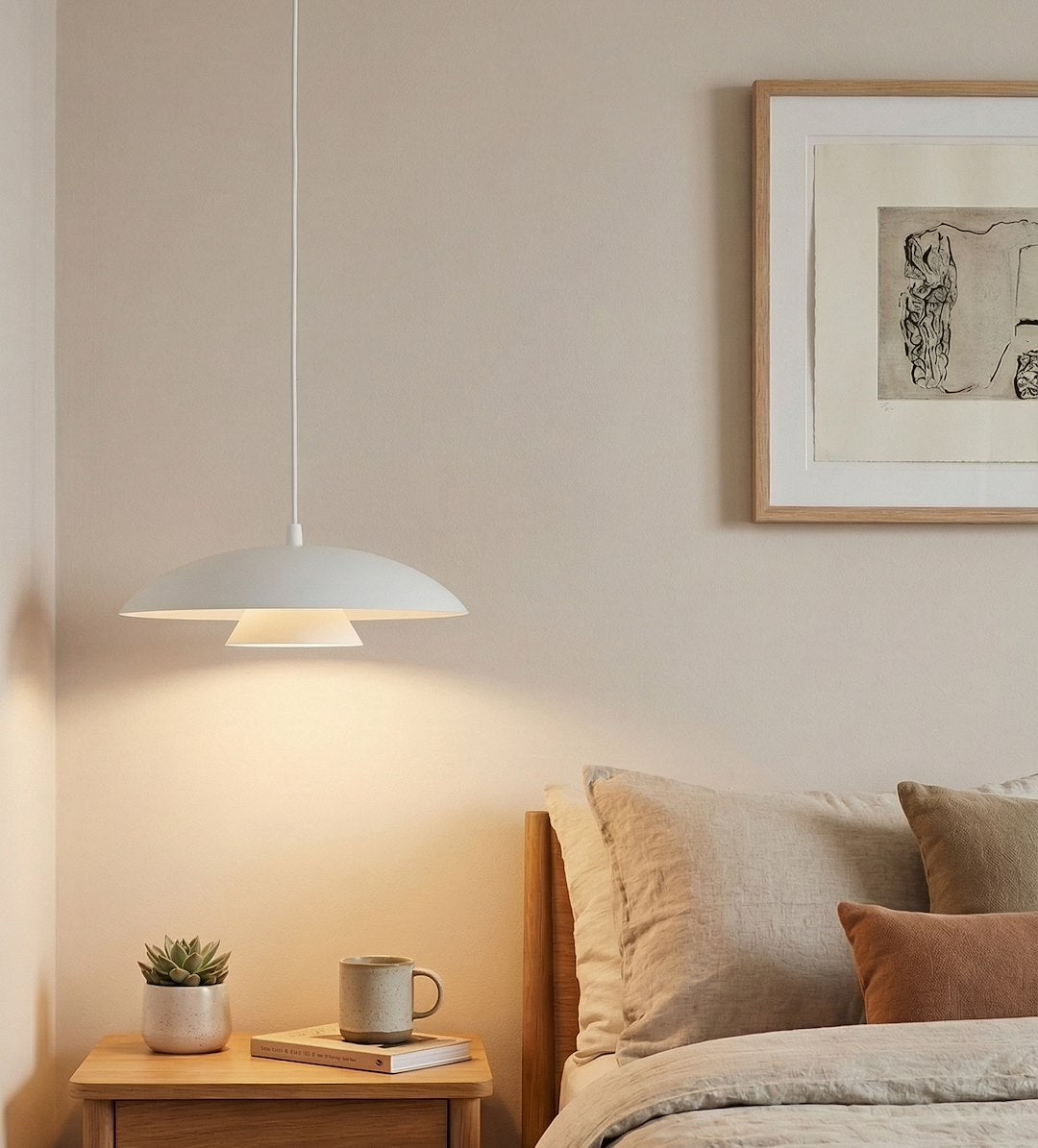 Mise en ambiance au-dessus d'une table de chevet, lumière chaude éclairant le mur beige