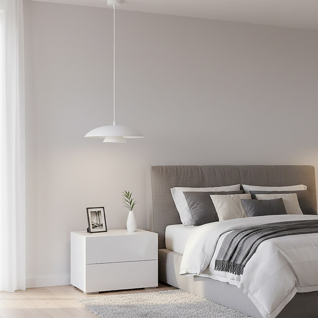 Luminaire suspendu au-dessus d'une table de nuit blanche dans une chambre grise épurée