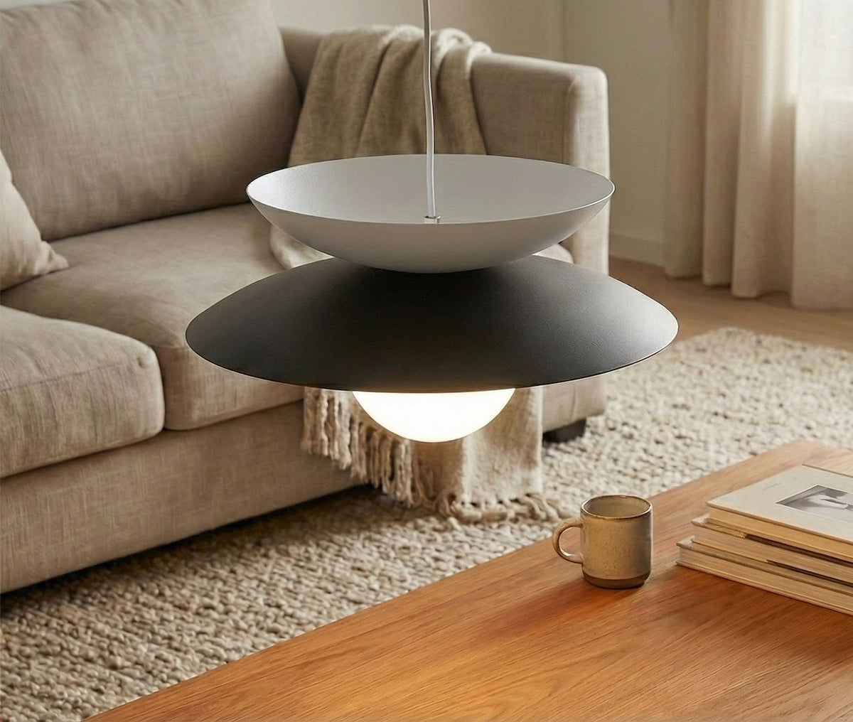 Mise en ambiance dans un salon beige, luminaire suspendu au-dessus de la table basse.
