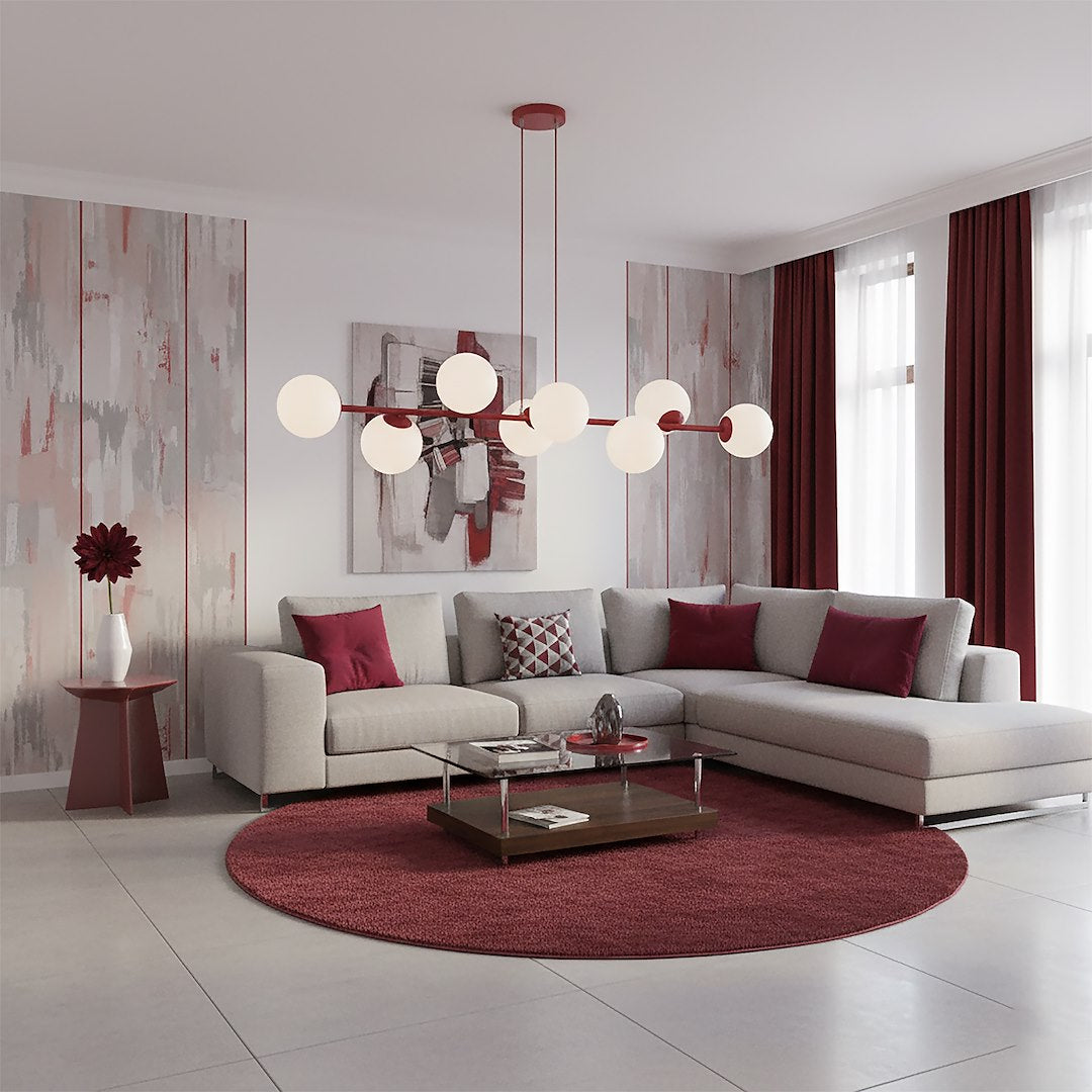 Vue d'ambiance d'un séjour avec canapé d'angle gris, tapis rond bordeaux et suspension allumée.
