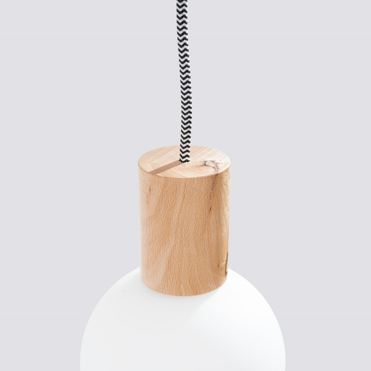 Gros plan sur la douille en bois et le câble textile tressé noir et blanc.