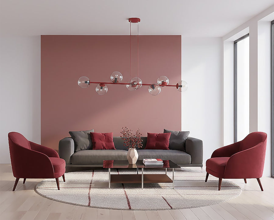Mise en ambiance salon, canapé gris, fauteuils bordeaux et mur rose poudré