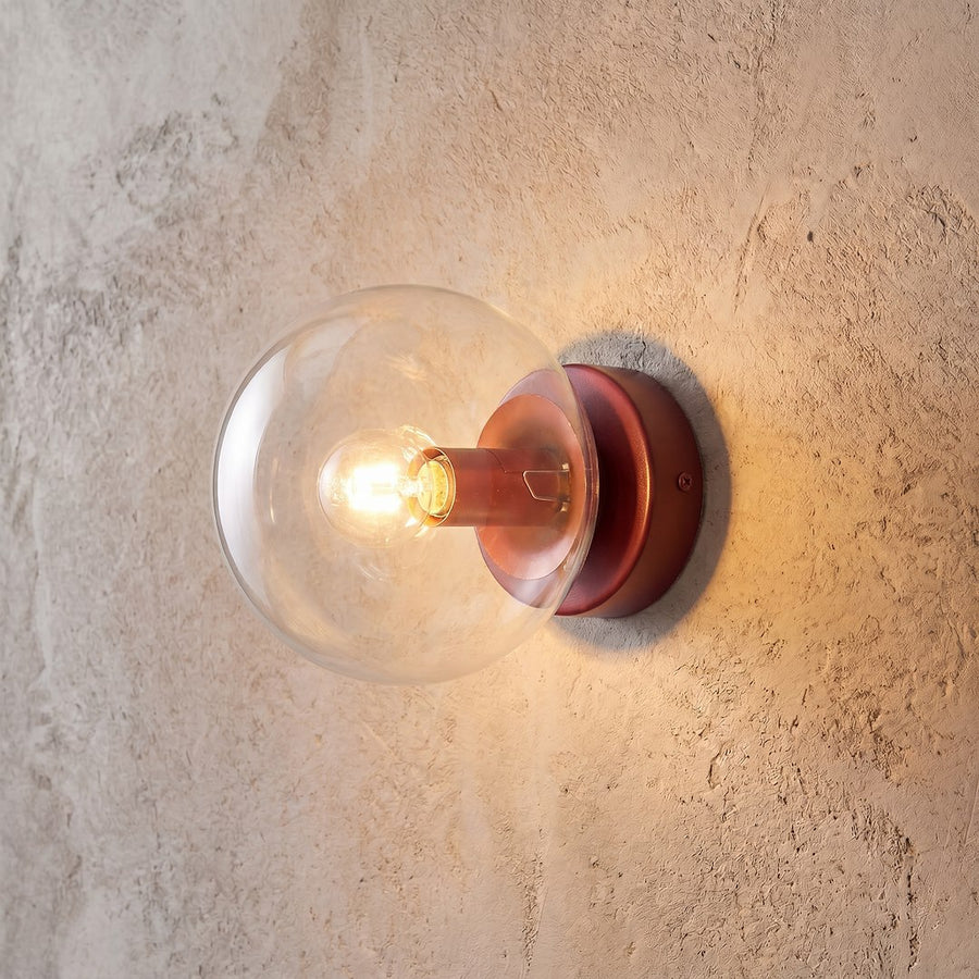 Gros plan de l'applique allumée, verre transparent et reflets sur mur texturé