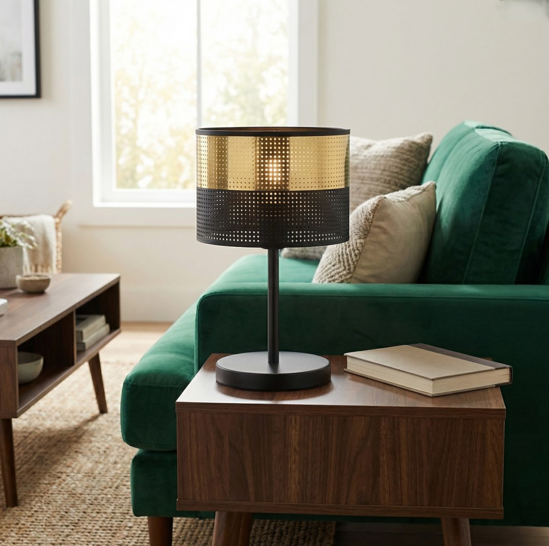 Lampe allumée sur table d'appoint devant un canapé vert bouteille près d'une fenêtre
