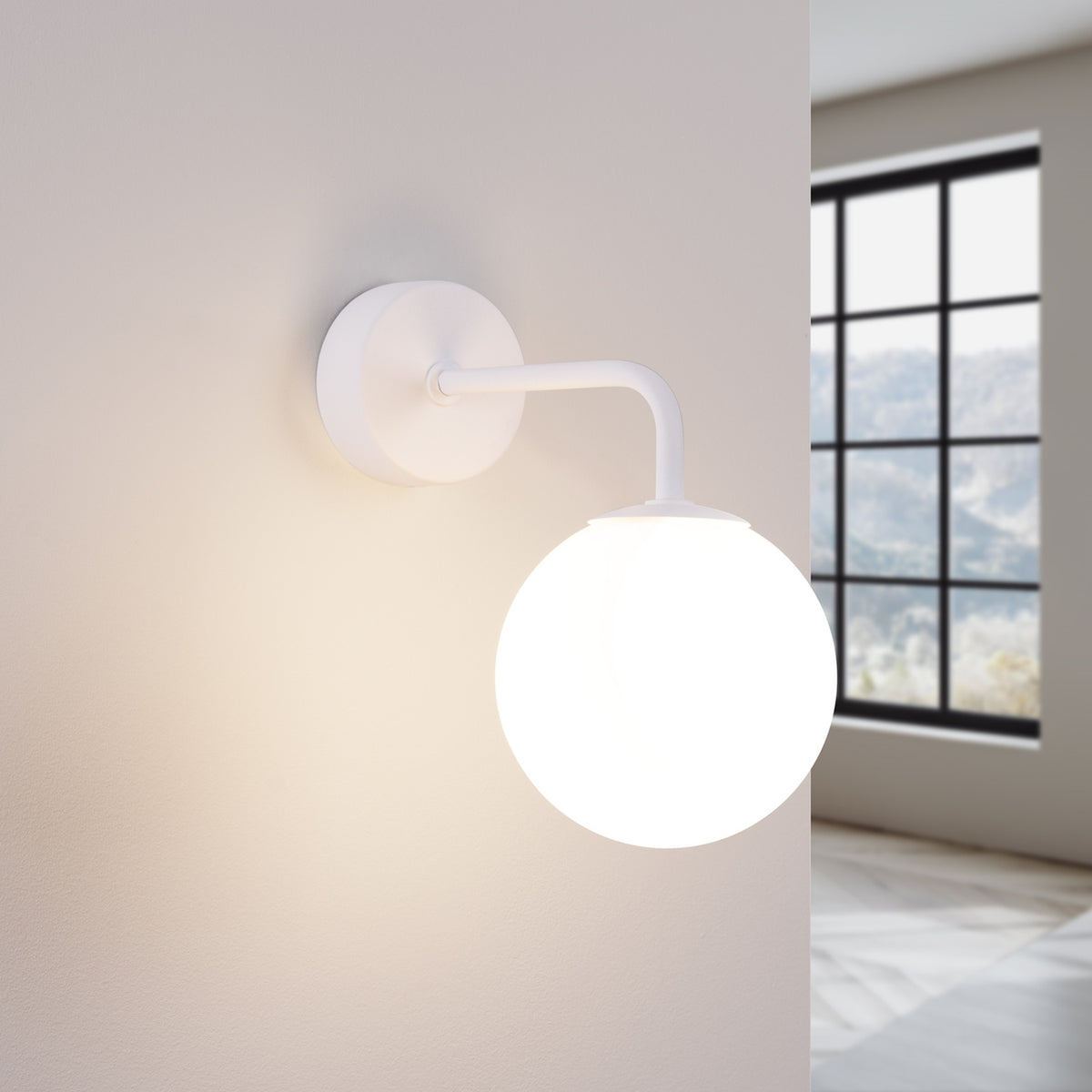 Applique murale blanche allumée diffusant une lumière chaude sur le mur, près d'une fenêtre.