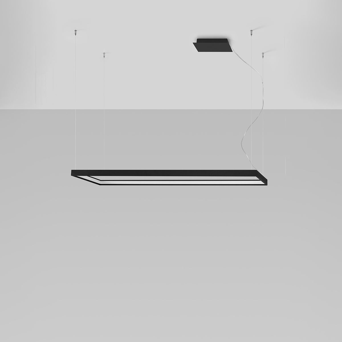 Vue en situation sur fond gris clair, luminaire rectangulaire noir suspendu par câbles.