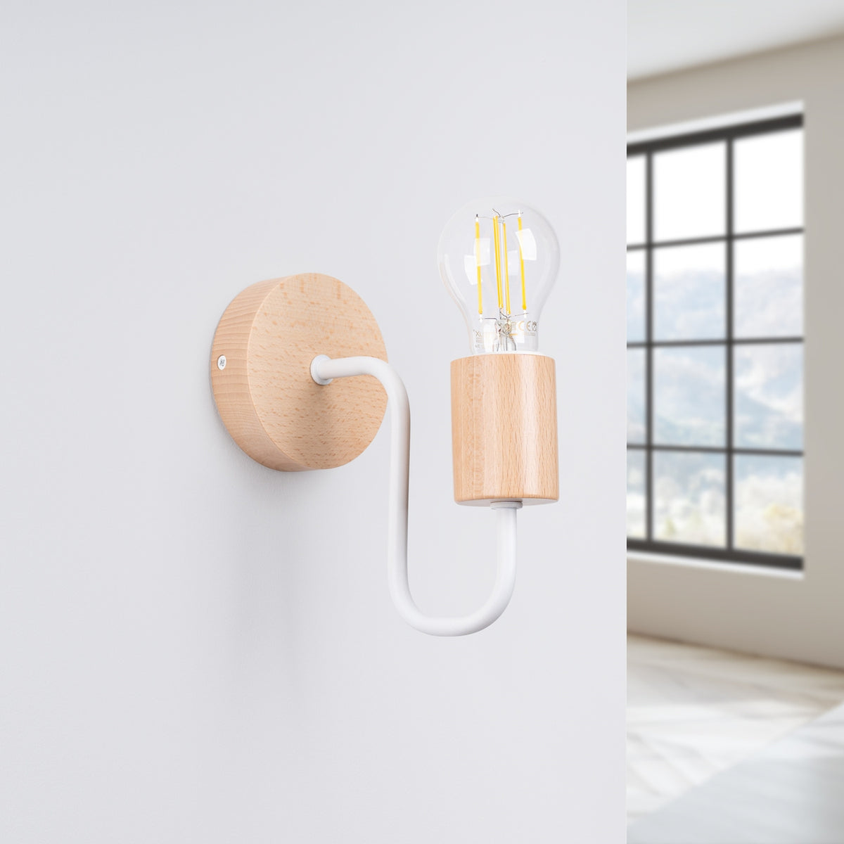 Applique fixée sur un mur blanc, près d'une fenêtre, dans une pièce lumineuse.