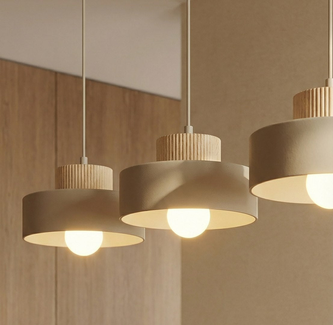 Gros plan sur les trois abat-jours beige et leurs couronnes en bois strié, ampoules allumées.