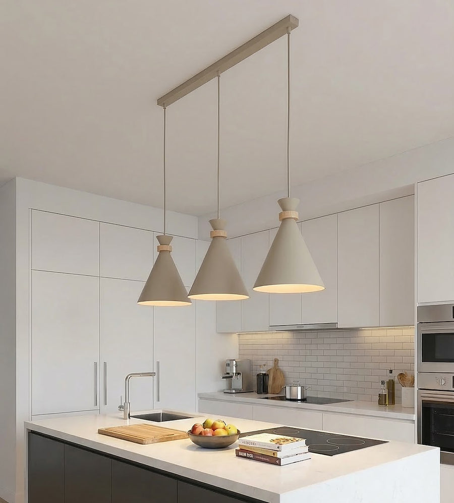 Ambiance cuisine blanche moderne, trois suspensions éclairées au-dessus de l'îlot central