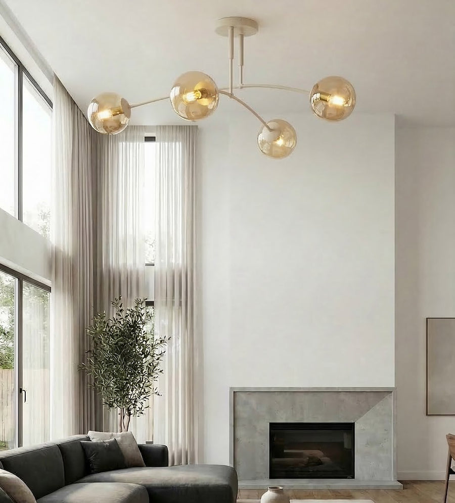 Le luminaire éclaire une pièce à cheminée, avec de grandes fenêtres et un canapé gris.