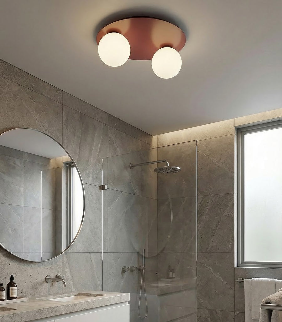 Ambiance salle de bain en pierre avec plafonnier bordeaux, douche, miroir et serviettes.