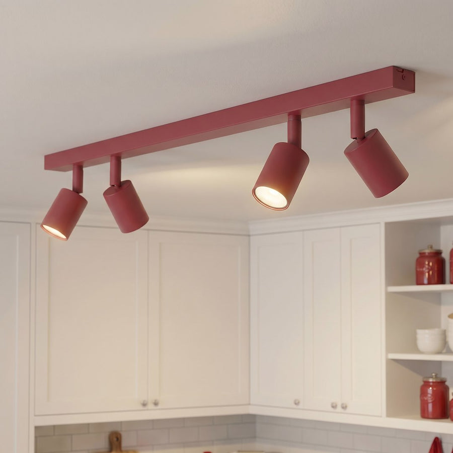 Luminaire bordeaux allumé au plafond, orienté vers des meubles de cuisine blancs