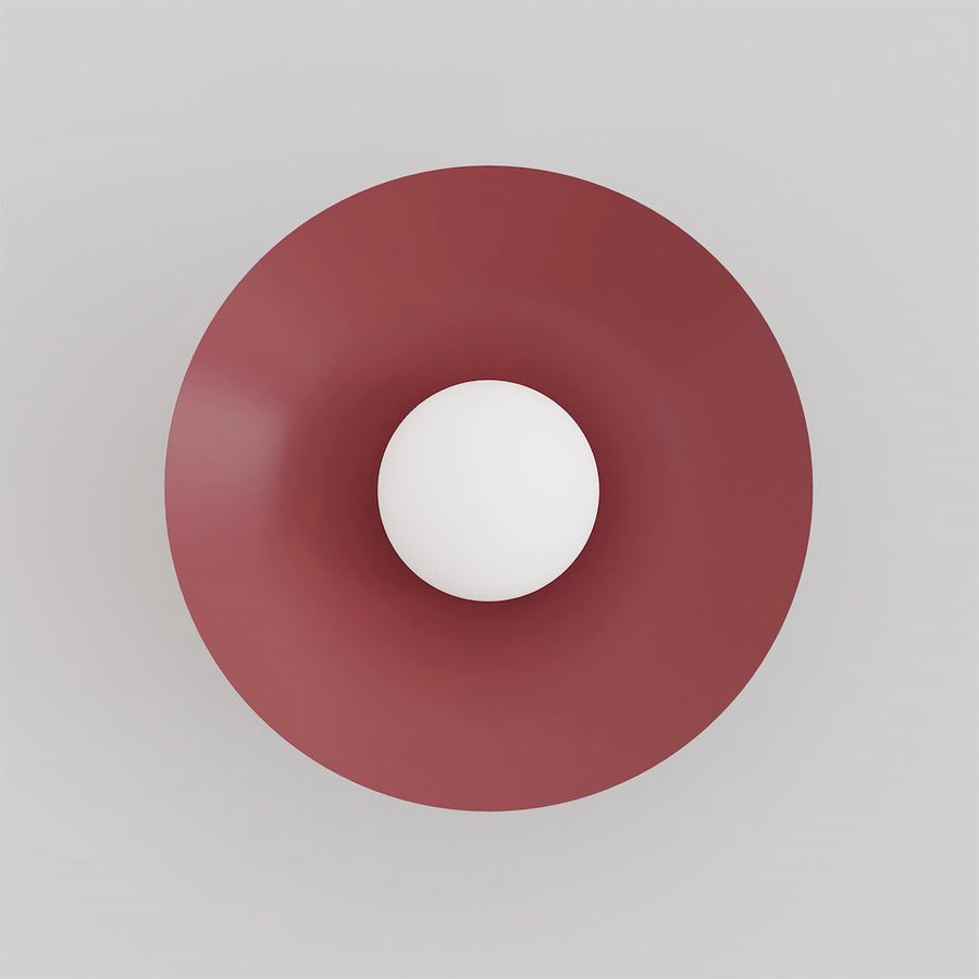Vue de face : grand disque bordeaux avec diffuseur sphérique blanc centré