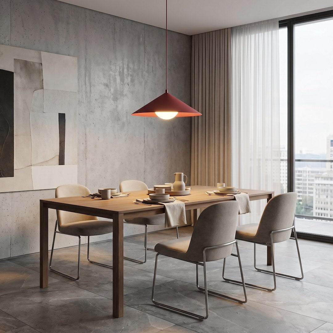 Table dressée près d'une baie vitrée, luminaire bordeaux en hauteur au-dessus des assiettes