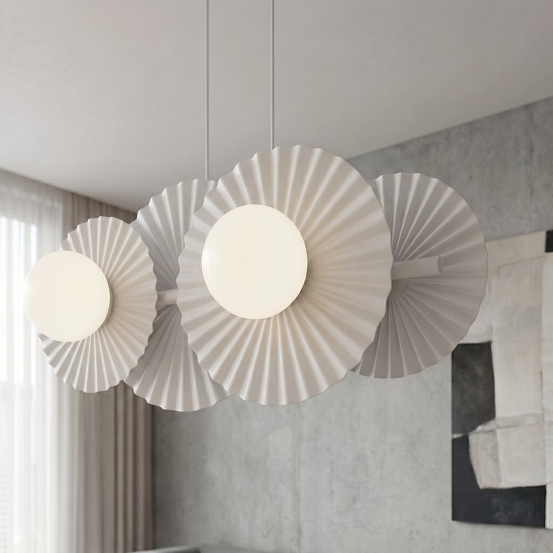 Gros plan sur les disques plissés et les globes opalins du luminaire allumé.