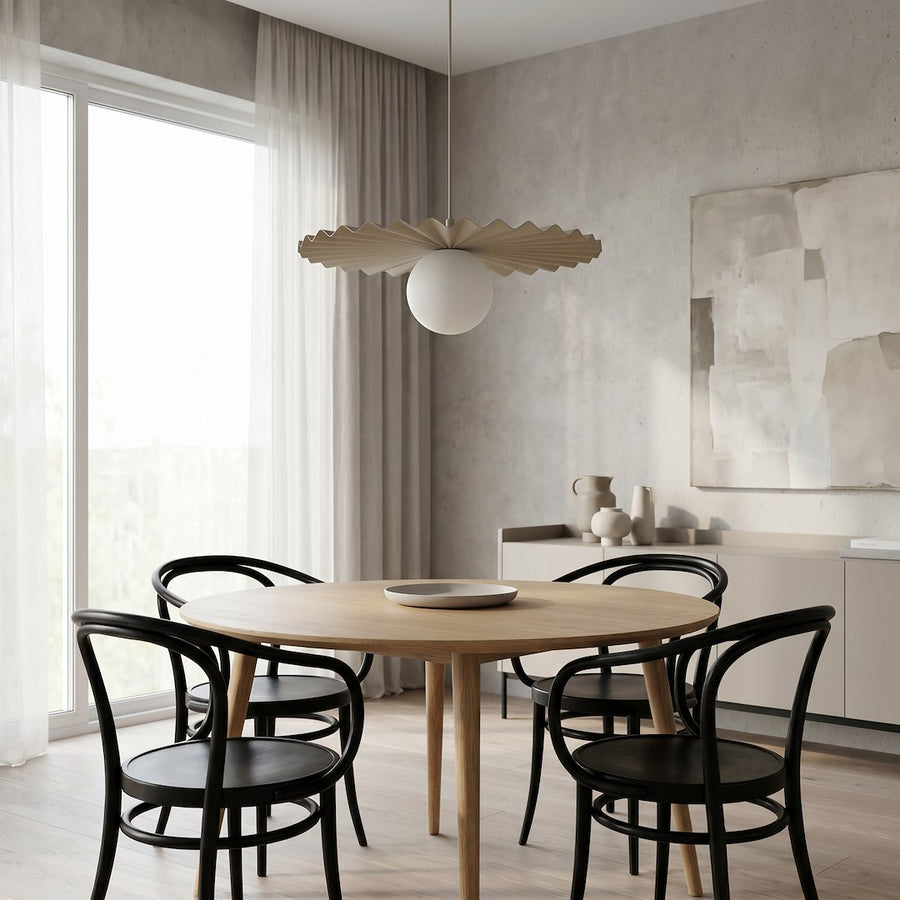 Pièce claire avec chaises noires, table en bois clair et suspension allumée
