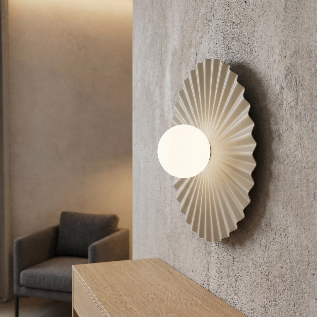 Mise en ambiance de l'applique allumée sur un mur texturé près d'un fauteuil.