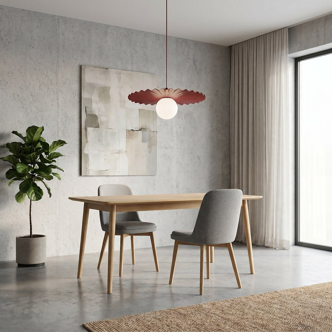 Suspension bordeaux installée au-dessus d'une table en bois dans une salle à manger.