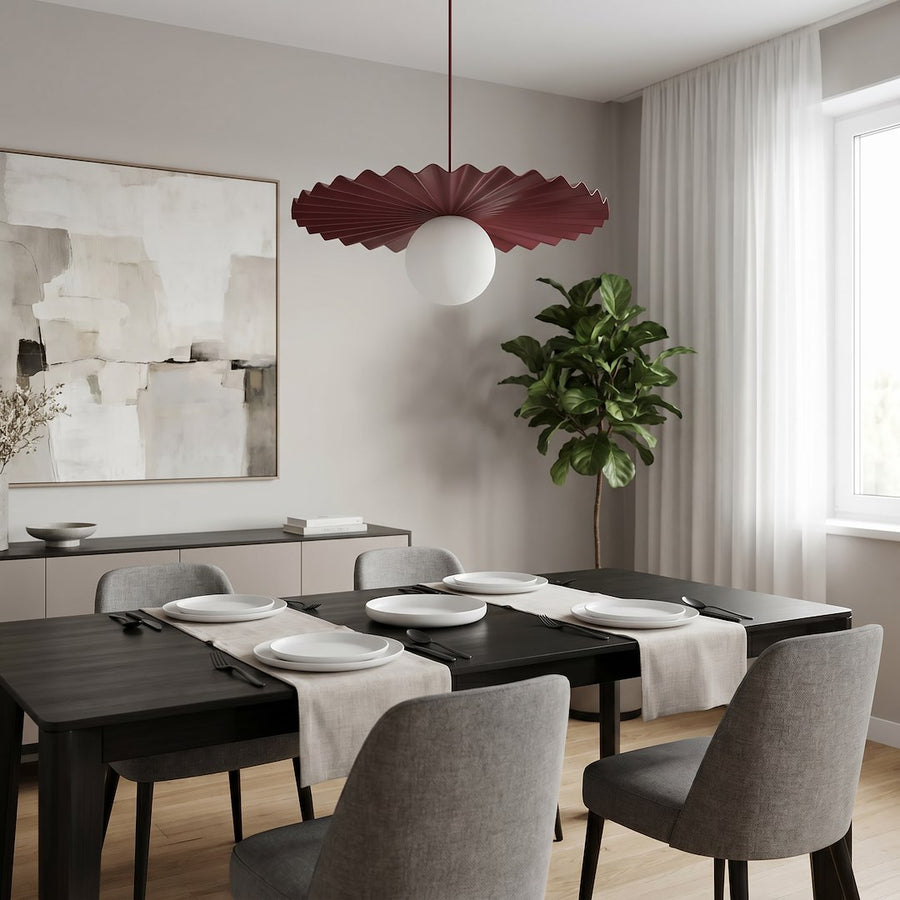 Luminaire suspendu bordeaux et blanc au-dessus d'une table noire dressée, intérieur moderne.
