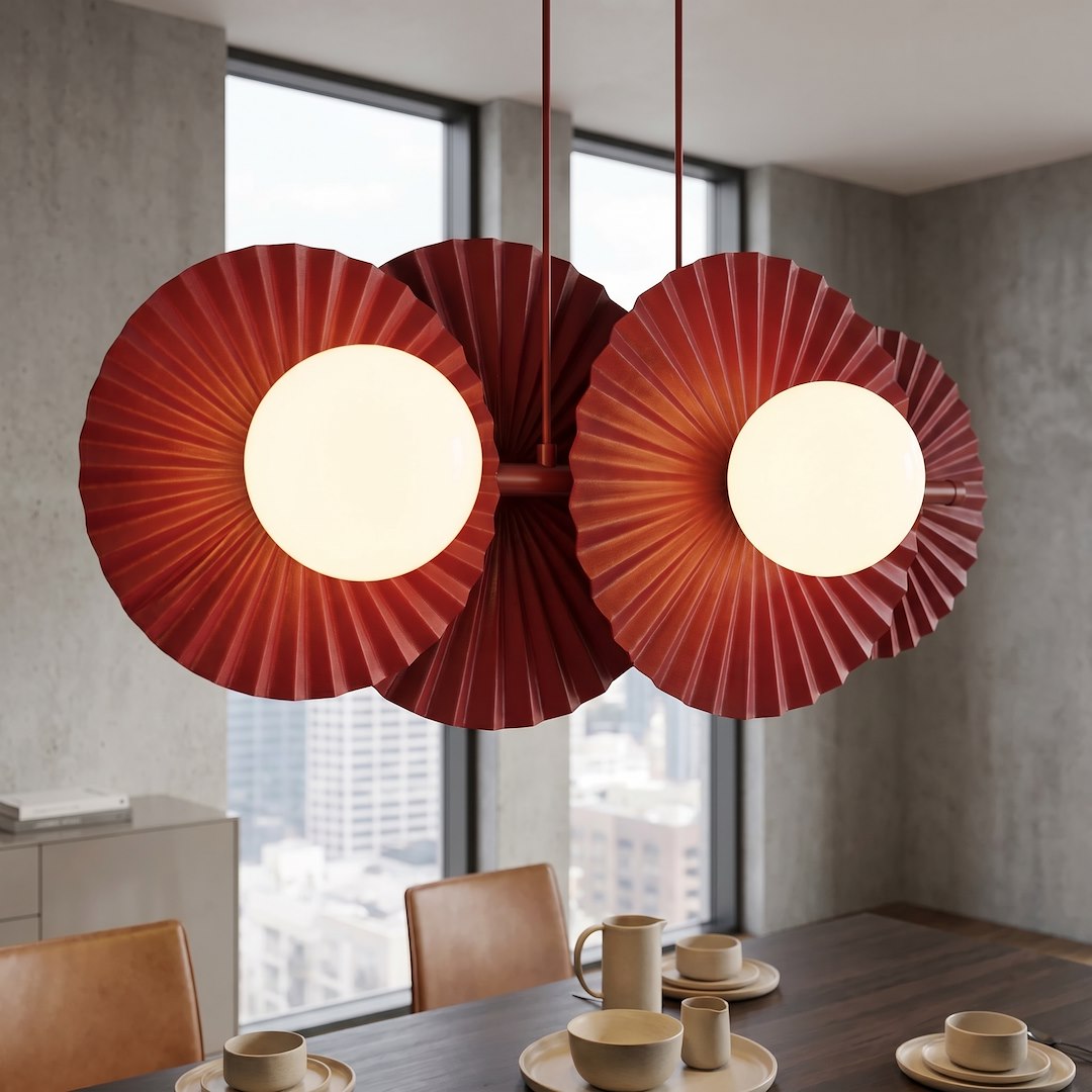Gros plan du luminaire allumé au-dessus d'une table, montrant les plis et les globes opalins.