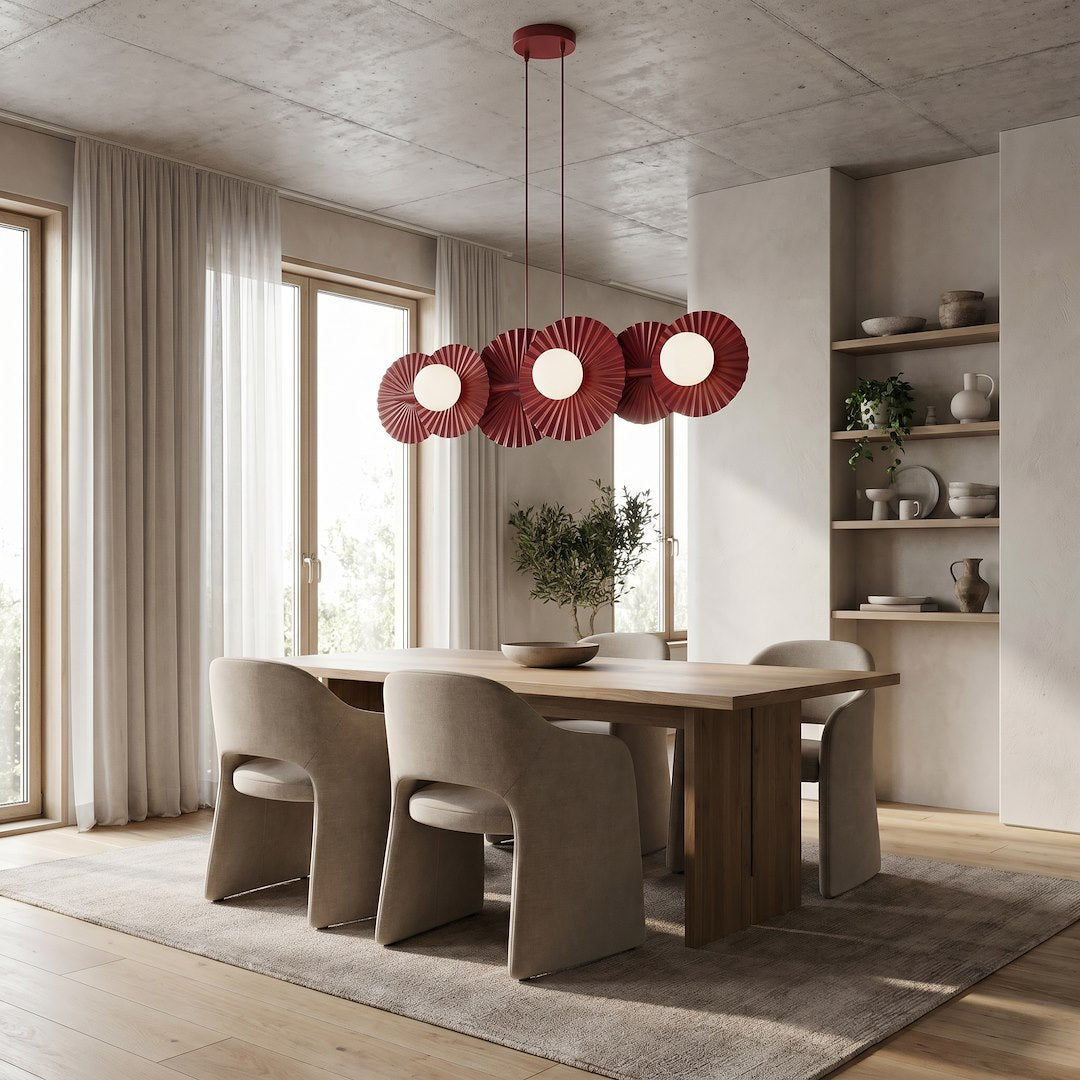 Suspension bordeaux installée au-dessus d'une table de salle à manger en bois clair, ambiance lumineuse.