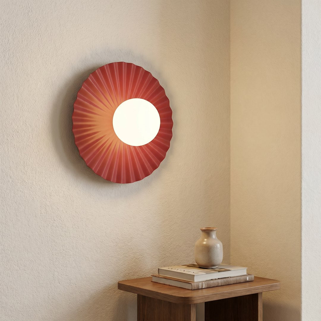 Mise en ambiance dans un coin, applique allumée éclairant une table en bois et un vase.