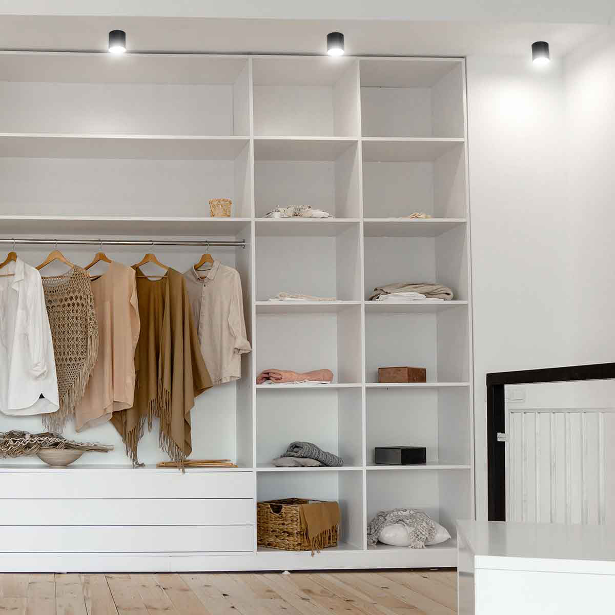 Mise en ambiance : spots noirs fixés au plafond devant une armoire blanche