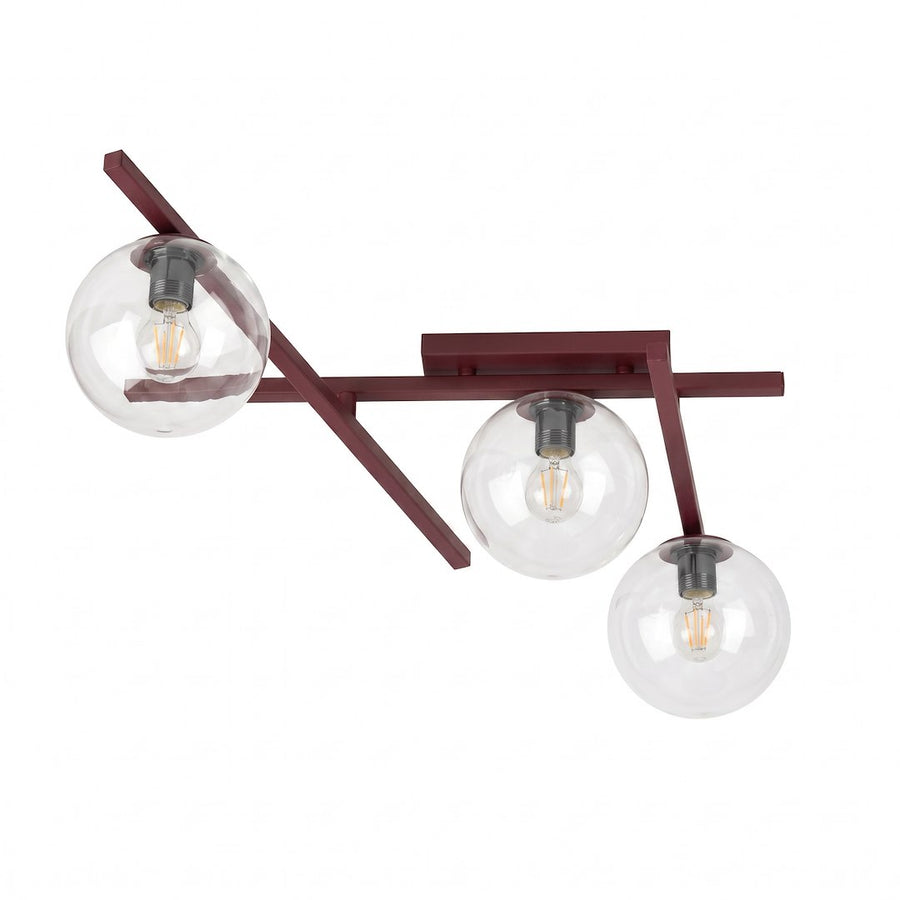Plafonnier trois globes en verre transparent montés sur bras métalliques croisés bordeaux, fond blanc.
