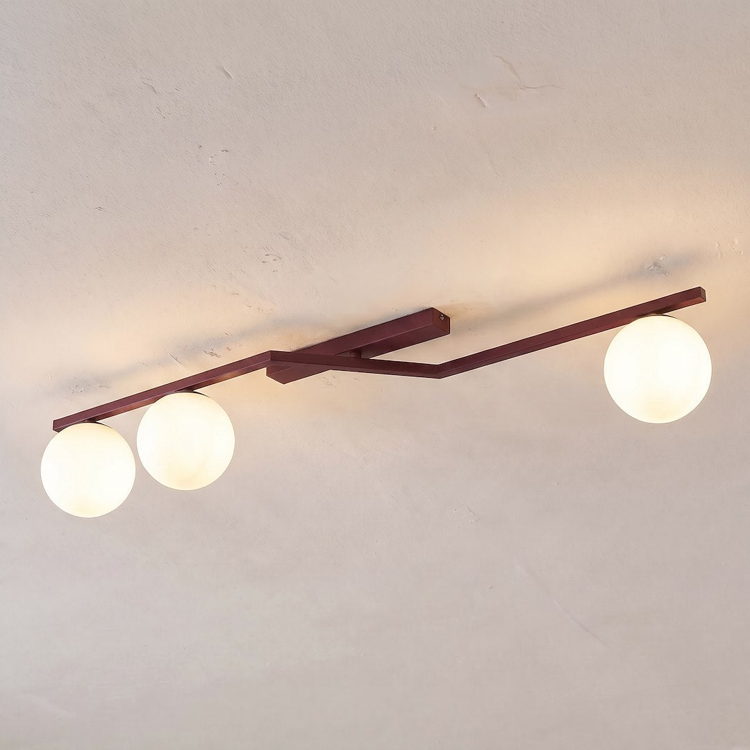 Plafonnier fixé au plafond, diffusant une lumière chaude à travers trois globes.