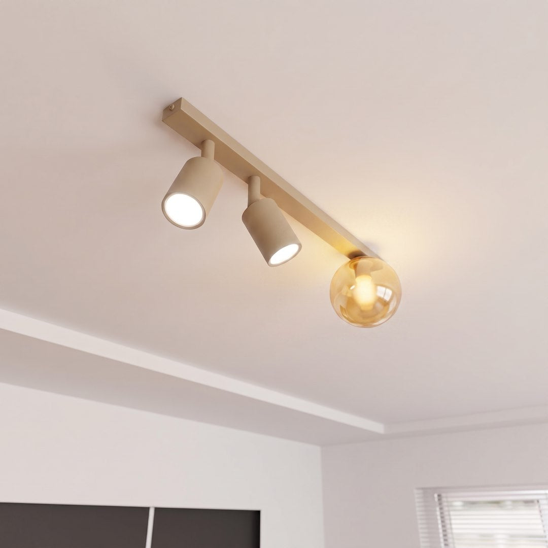 Vue rapprochée du plafonnier beige allumé, spots orientables et globe ambré sous le plafond.