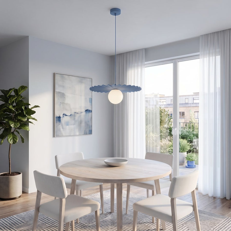 Suspension bleue éclairée au-dessus d'une table ronde dans une salle à manger.