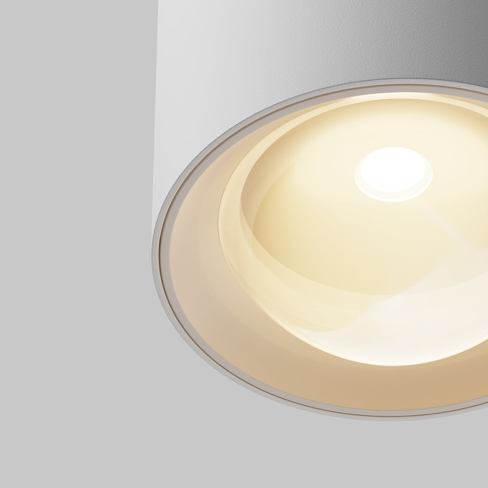Détail rapproché du diffuseur et de la source LED chaude sous le cylindre blanc.