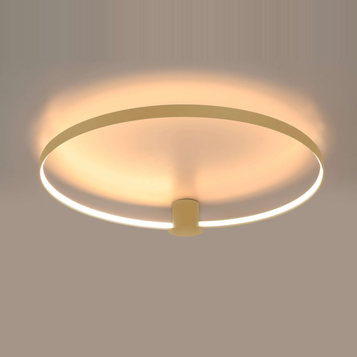 Vue par dessous du plafonnier allumé, halo chaud et anneau LED périphérique lumineux.