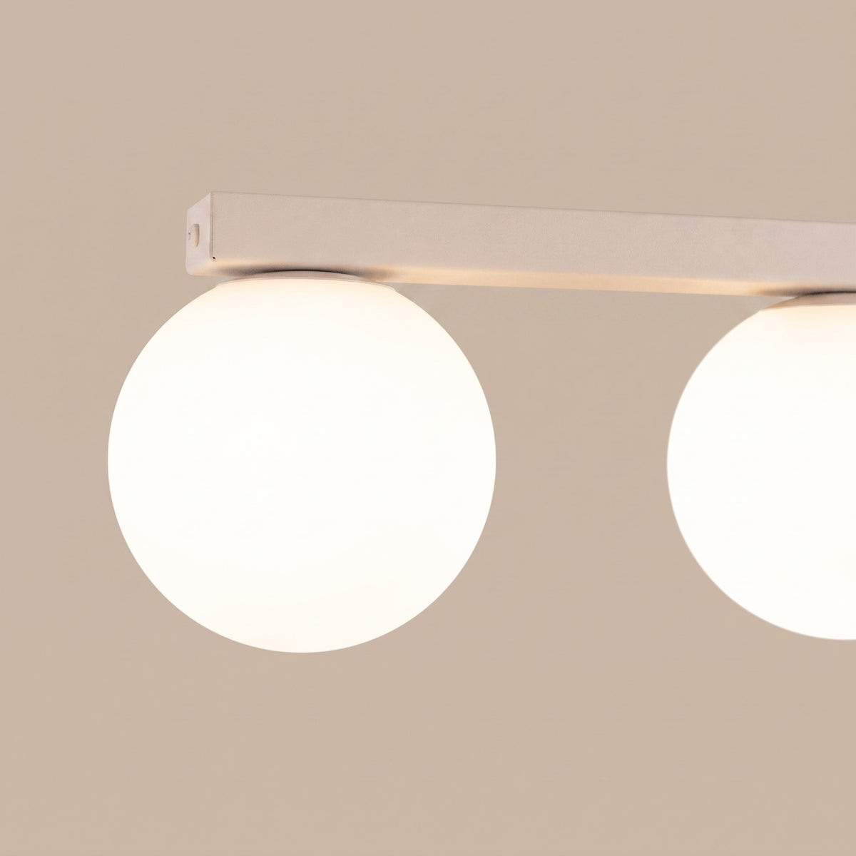 Détail rapproché de deux globes allumés sous la barre beige, ambiance chaleureuse.