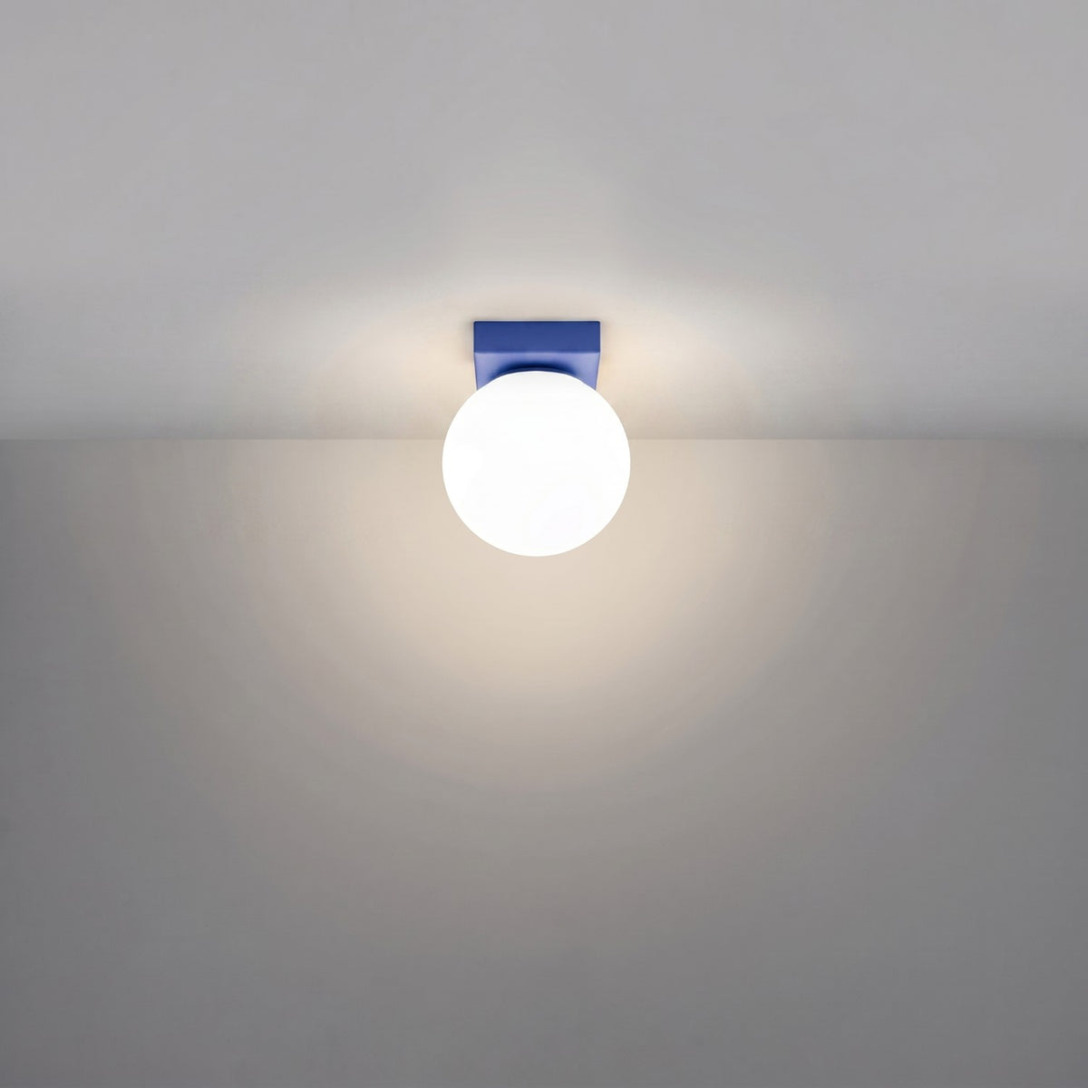 Plafonnier allumé au plafond, halo lumineux diffus autour du globe blanc.