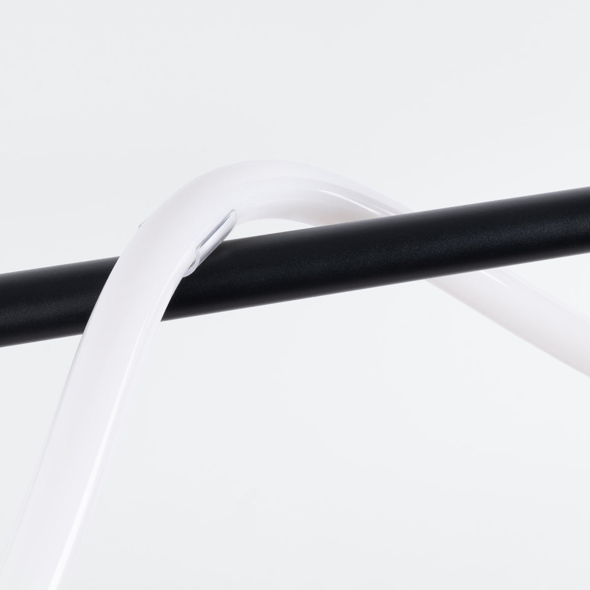 Détail du croisement entre le ruban LED blanc et la barre noire maintenue par un clip