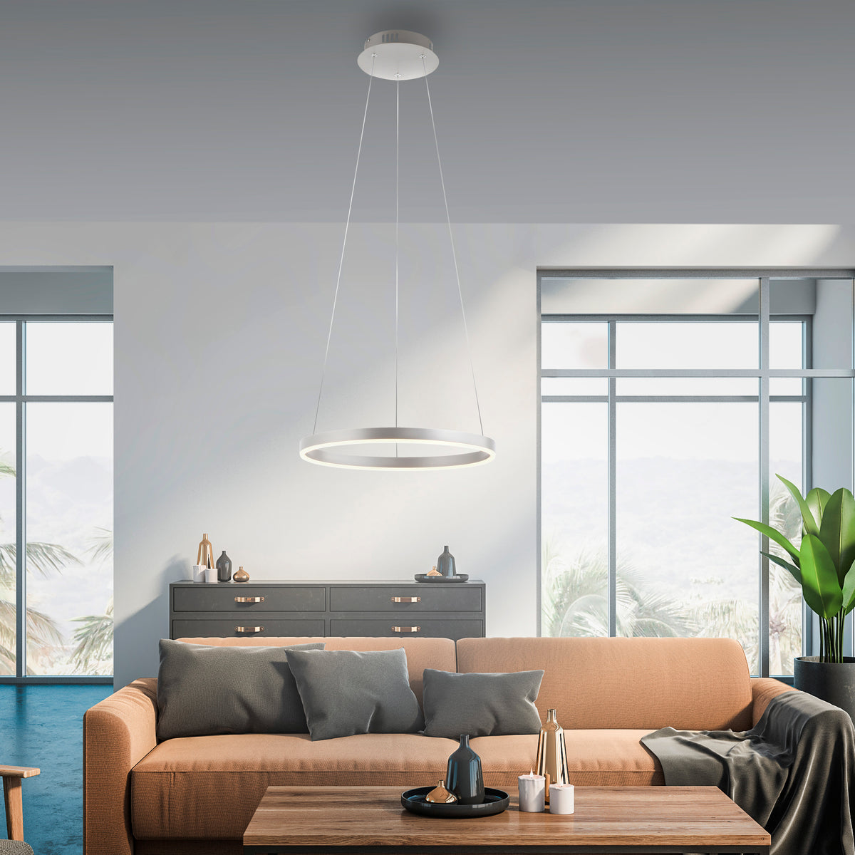 Mise en ambiance dans un salon moderne avec canapé, suspension annulaire éclairant la pièce.