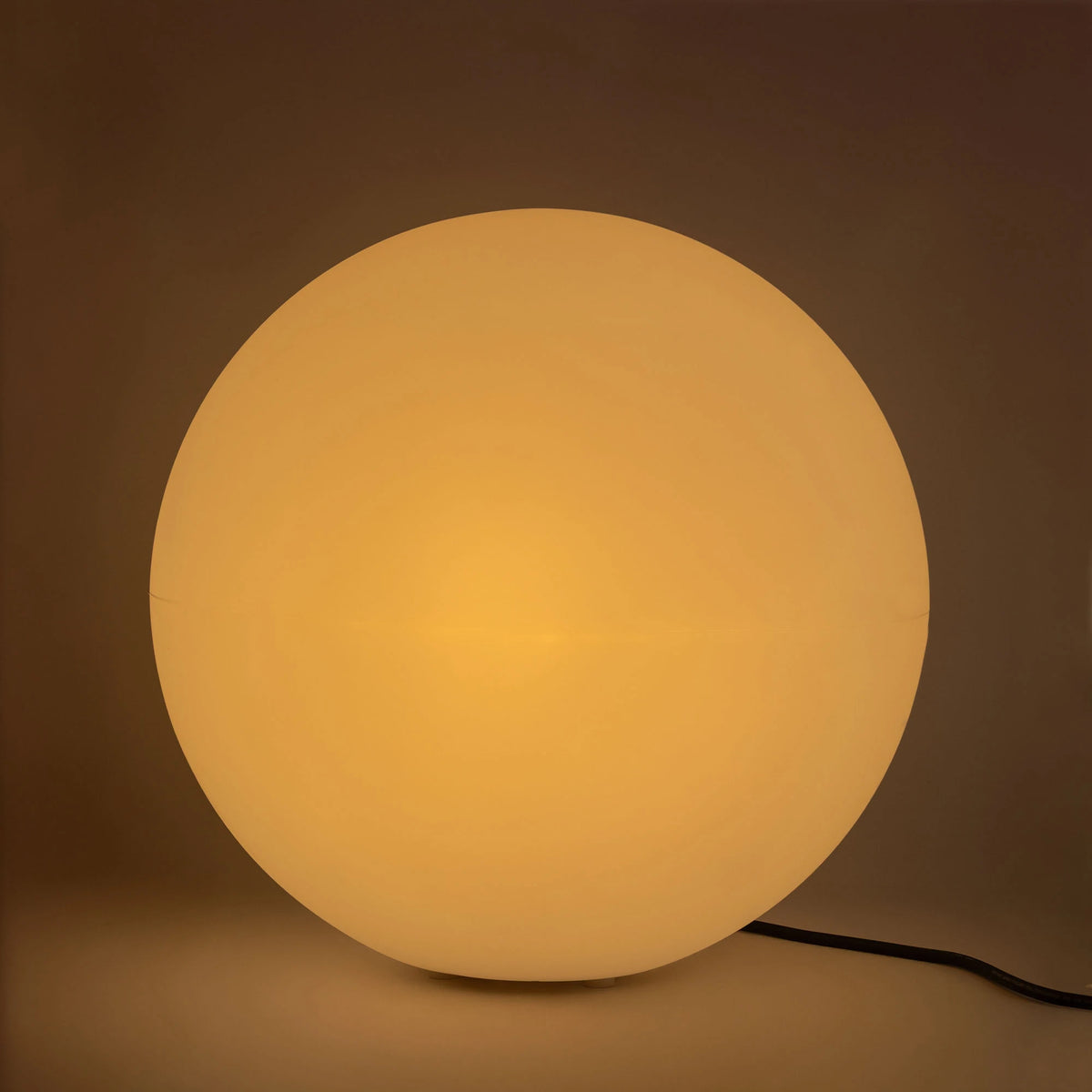 Globe lumineux allumé diffusant une lumière chaude ambrée dans une pièce sombre