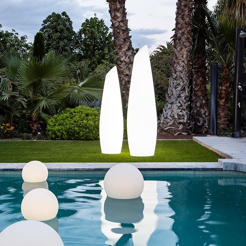 Lampadaires blancs sur pelouse au bord du bassin avec sphères lumineuses flottantes