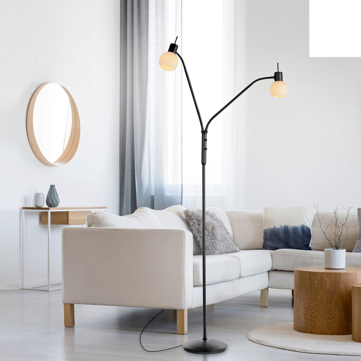 Mise en ambiance dans un salon clair avec canapé beige et miroir rond.